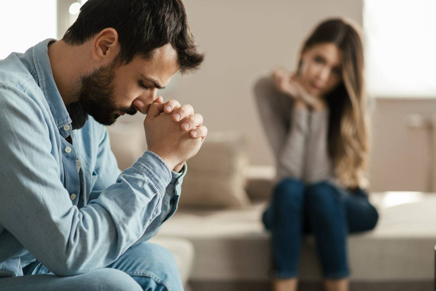 Young man feeling sad after arguing with his girlfriend  on sofa at home.